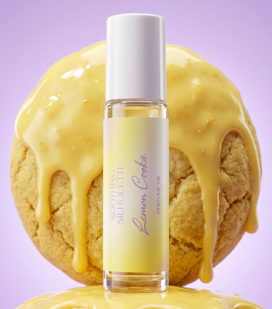Lemon Cookie 10 milliliter perfume oil bottle.  Two large lemon cookies with lemon icing as photo props on a light purple background. Original Price: $14. Comes in a roll-on glass bottle. Notes are lemon, sugar cookie and vanilla. Ingredients are Isopropyl Myristate and Fragrance