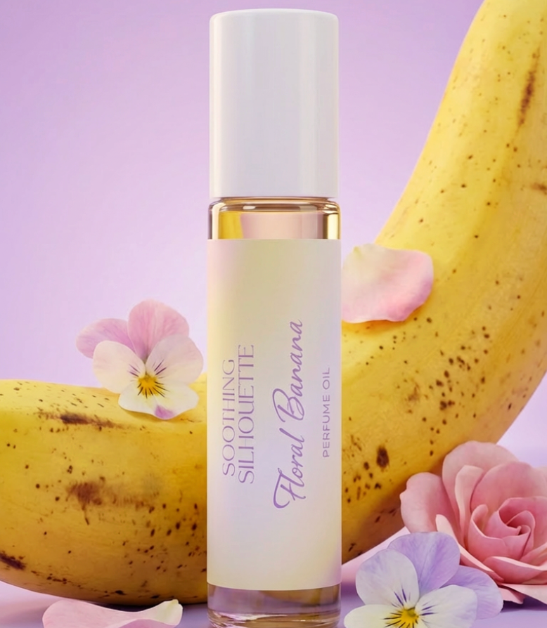 Floral Banana 10 milliliter perfume oil bottle. A banana and flowers as photo props on a light purple background. Original Price: $14. Comes in a roll-on glass bottle. Notes: banana, strawberry, cantaloupe, and sugary vanilla. Ingredients are Isopropyl Myristate and Fragrance