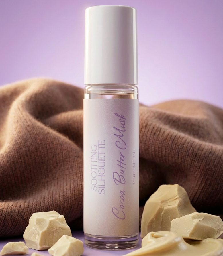 Cocoa Butter Musk 10 milliliter perfume oil bottle. Brown sweater and cocoa butter as photo props on a light purple background. Original Price: $14. Comes in a roll-on glass bottle. Notes are tonka, coconut, jasmine, cocoa butter, cedarwood, sandalwood, amber, musk. Ingredients are Isopropyl Myristate and Fragrance