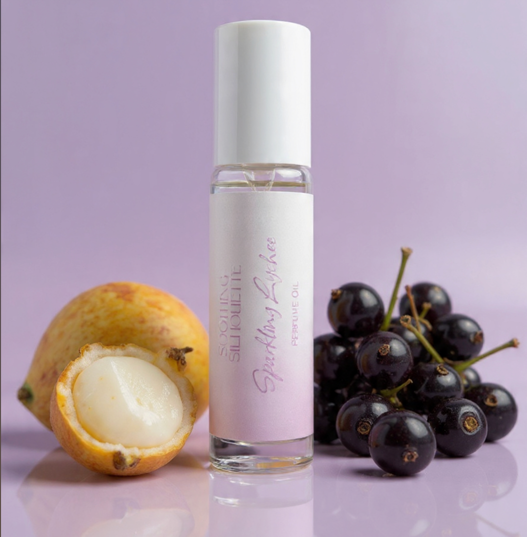 Sparkling Lychee 10 milliliter perfume oil bottle.  Lychees and black currants as photo props on a light purple background. Original Price: $14. Comes in a roll-on glass bottle. Notes are lychees, lemons, black currants, floral, musk and vanilla. Ingredients is Isopropyl Myristate and Fragrance